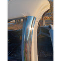 Close-up of a chrome car bumper with a blurred outdoor background. 1955-1957 Chevy 2-Door Hardtop, Pillar Trim, Pair, Stainless.