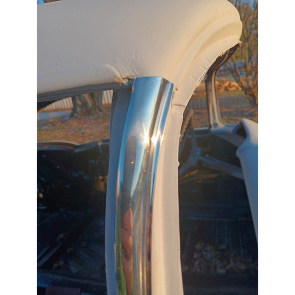 Close-up of a chrome car bumper with a blurred outdoor background. 1955-1957 Chevy 2-Door Hardtop, Pillar Trim, Pair, Stainless.