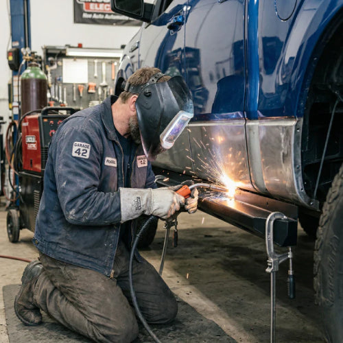 Technician welding rocker panel replacement on truck